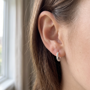 Silver 925 sterling silver huggie hoop earring worn on a single ear in natural daylight, no other jewelry in frame