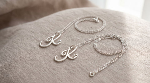 Two sterling silver pendant necklaces of different chain lengths laid side by side to compare fit.