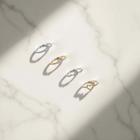 Adjustable open-back sterling silver and gold rings for women arranged on marble