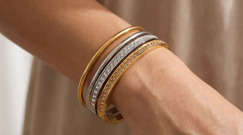 Woman's wrist stacked with gold and silver bangle bracelets