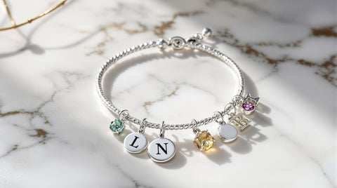 Best charm bracelets for women — sterling silver with initial and birthstone charms on marble surface
