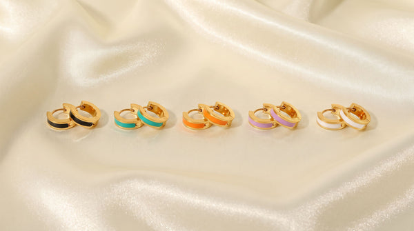 Five pairs of gold-plated enamel-inlay hoop earrings in black, teal-green, orange, lilac and white, arranged together