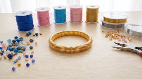 Flat lay of beading cord spools and colorful beads for making beaded bracelets
