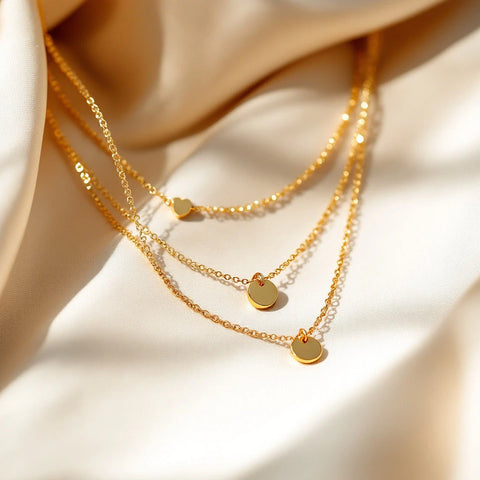 Several thin gold dainty necklaces layered on a neutral background