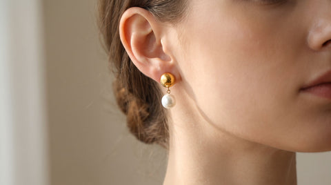 Close-up of a woman wearing a gold-plated pearl drop earring