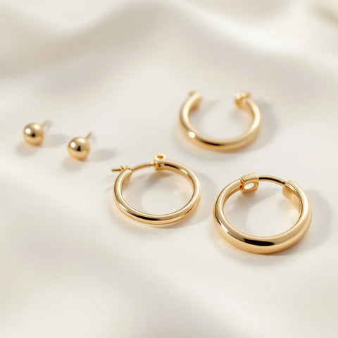 Several gold hoop earrings in different sizes arranged on a neutral background