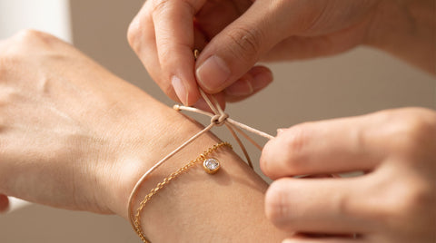 Close-up of hands tying a secure knot on a cord bracelet