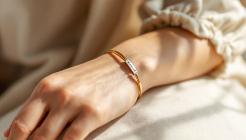 Woman's wrist wearing a medical alert bracelet stacked with a slim gold bangle