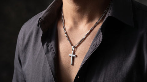 Men's stainless steel cross pendant on a cuban link chain worn over a dark shirt