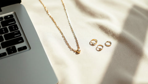 Sterling silver and gold-plated jewelry pieces arranged near a laptop, representing online jewelry shopping