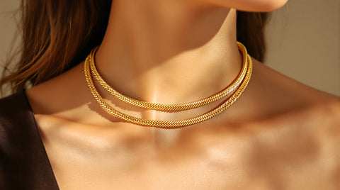 Woman wearing an 18K gold PVD-coated double-row snake chain necklace at the collarbone, close-up styling shot