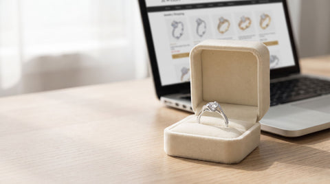 Sterling silver CZ solitaire engagement ring in an open ring box beside a laptop