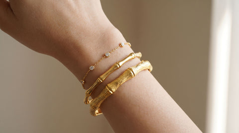 Woman's wrist wearing a stacked set of three mixed gold bracelets of varying width