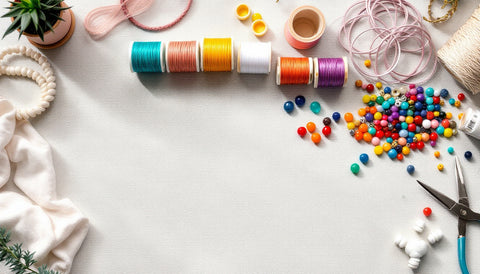 Flatlay of beading string spools, loose beads, and jewelry-making tools for stringing beaded bracelets