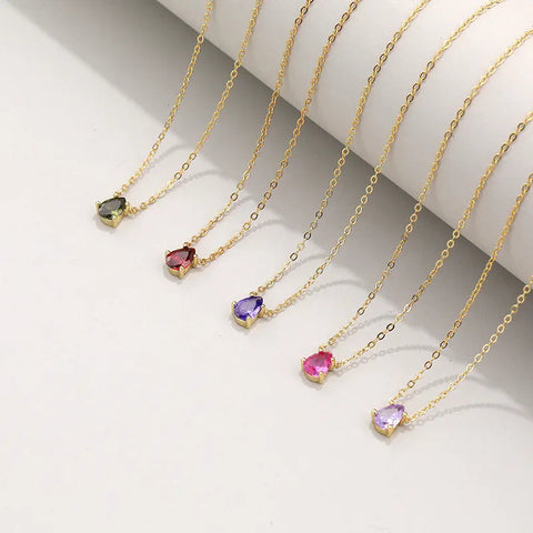 Five teardrop birthstone pendant necklaces in peridot green, garnet red, amethyst purple, ruby pink, and lavender draped together -- 925 sterling silver, 18K gold plated