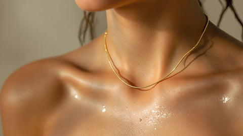 Woman wearing a waterproof gold snake chain necklace with water droplets on skin