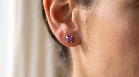 Close-up of a birthstone stud earring worn in an ear, sterling silver setting