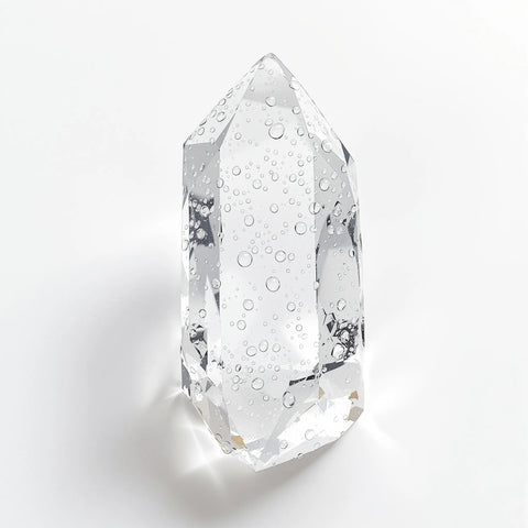 Clear quartz crystal point with water droplets showing brilliant transparency on white background