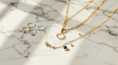 Flat-lay photograph of mixed gold-tone and silver-tone jewelry pieces styled together on white marble