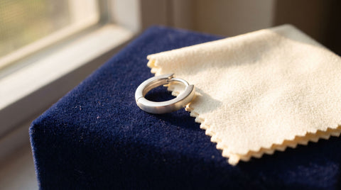 925 sterling silver hoop earring beside a polishing cloth, illustrating silver jewelry care