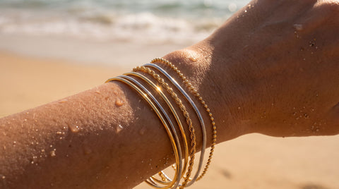 Stack of gold and silver bracelets on a wrist at the beach
