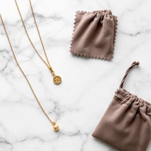 Gold jewelry care essentials: microfiber cloth, anti-tarnish pouch, and gold necklace