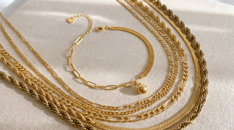 Layered gold jewelry pieces on a neutral background showing the contrast between dulled tarnished plating and bright polished tarnish-free jewelry
