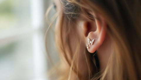 Close-up of a delicate butterfly-shaped stud earring worn on the ear