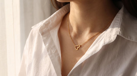 Small open outline gold heart necklace worn at the base of the neck, an Elsa Peretti Open Heart look-alike in gold-plated sterling silver