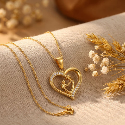 Gold mother and child heart pendant necklace styled on linen with dried flowers, a first Mother's Day gift