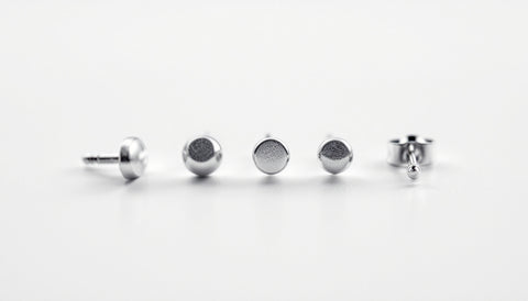 A row of stud earrings of different thicknesses laid out for size comparison