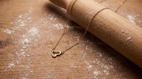 Delicate gold heart necklace styled as a baker gift with a rolling pin
