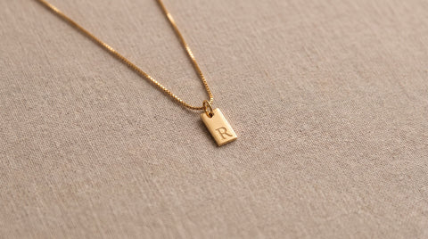 Small gold initial tag necklace styled as an understated gift for introverts
