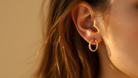 Woman wearing gold hoop earrings, close-up jewelry photography