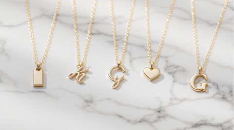 Gold initial pendant necklaces on a marble surface