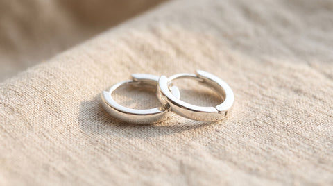 Close-up of polished 925 sterling silver hoop earrings resting on a soft cloth