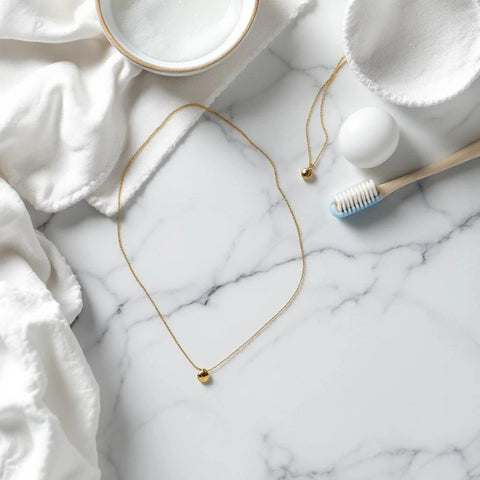 How to clean gold plated jewelry at home — supplies laid out on white marble