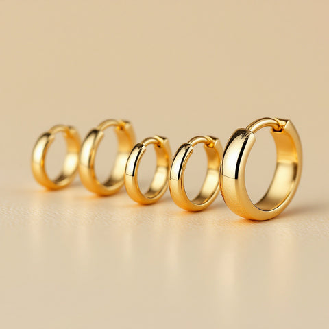Huggie earring sizes from 6mm to 14mm arranged in a row on cream background