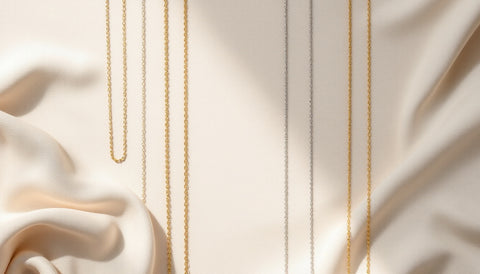 Several sterling silver and gold-plated chain necklaces laid out on a neutral surface