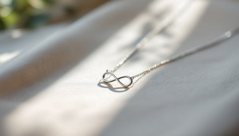 Sterling silver infinity pendant necklace on a neutral fabric background