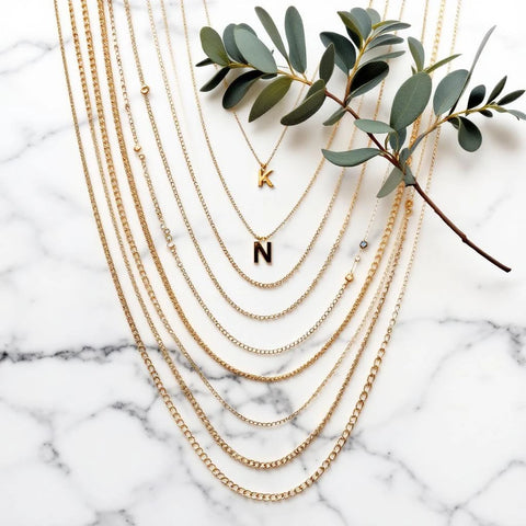 Complete guide to initial necklaces — chain types, lengths and layering on marble