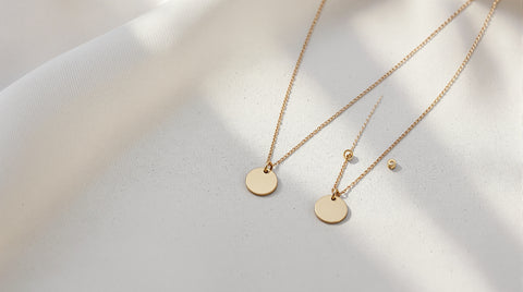 Minimalist gold demi-fine necklaces and earrings laid out for a brand legitimacy review
