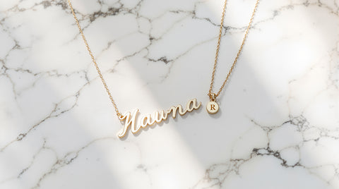 Gold-plated personalized nameplate necklace laid flat next to an initial pendant for an Oak and Luna legitimacy review