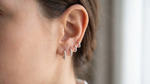 Close-up of a woman's ear wearing hypoallergenic silver huggie earrings