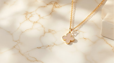 Elegant gold clover pendant necklace on white marble, luxury jewelry photography
