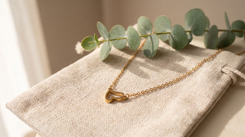 Gold-plated sterling silver initial pendant necklace styled on a linen pouch