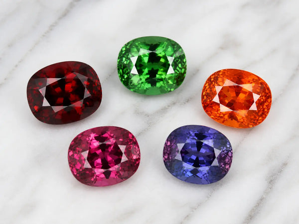 January birthstone garnet — red, green, orange and color-change varieties on white surface