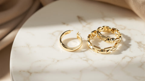 Gold ear cuff earring and chunky gold hoop earrings on white marble, Jenny Bird inspired statement jewelry styling