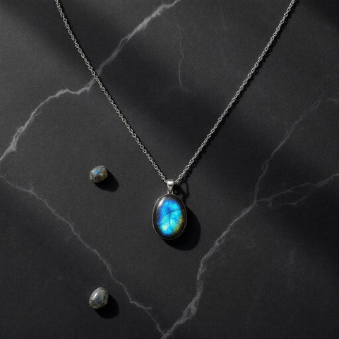 Labradorite pendant necklace showing vivid blue-green iridescent flash on dark marble — labradorite meaning guide