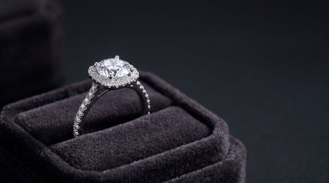 Halo ring resting upright in a dark velvet ring box, dramatic side lighting